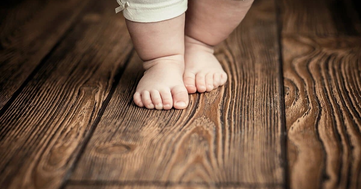 Fußbodenheizung Kinderfüße auf dunklem Dielenboden