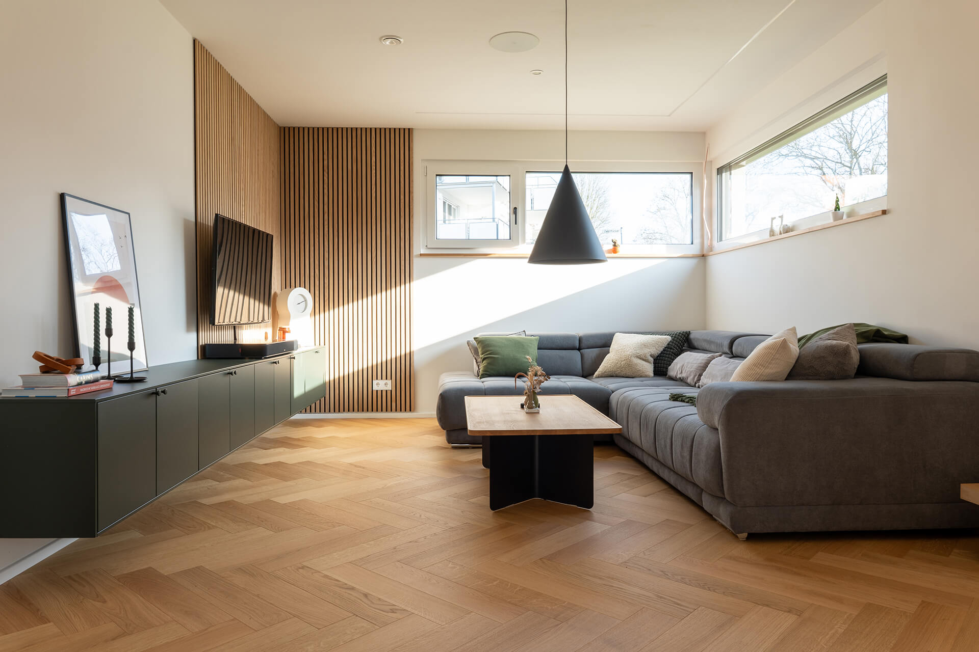 comfort-tabis-xl-eiche-elegance-geölt-fischgrat-2 Wohnzimmer mit Comfort Tabis XL Fischgrat, dunkelgrünem Sideboard und schwarzer Kegelpendelleuchte